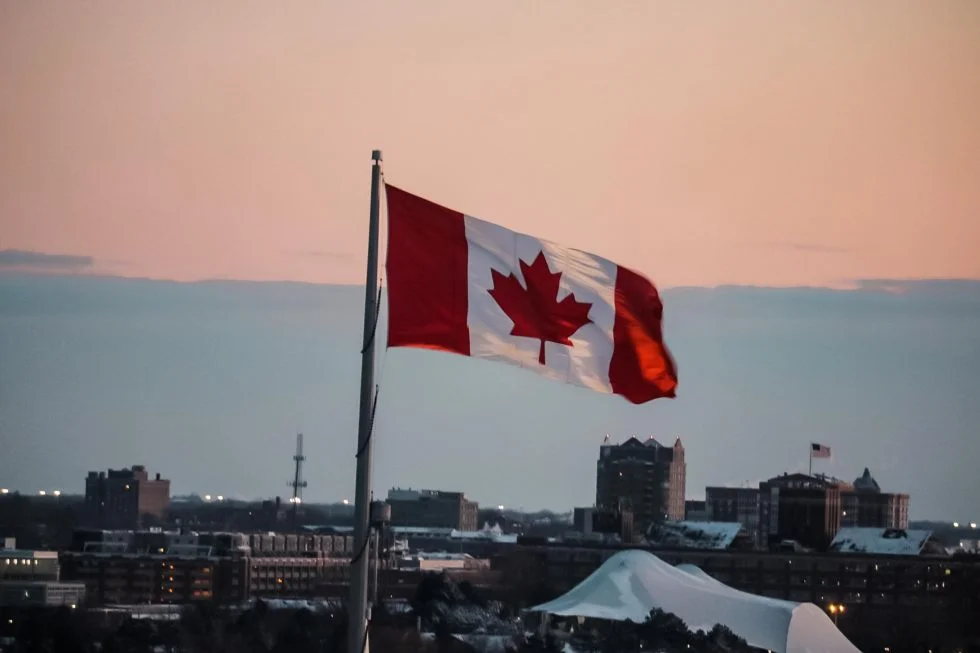 Canadian flag with city skyline at dusk